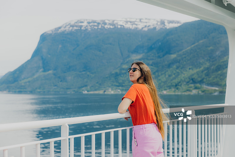 愉快的女性思考夏季旅行，乘渡轮穿越峡湾图片素材