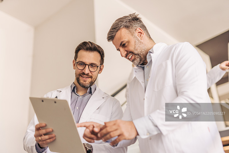 两位医生在医院走廊讨论病历。图片素材