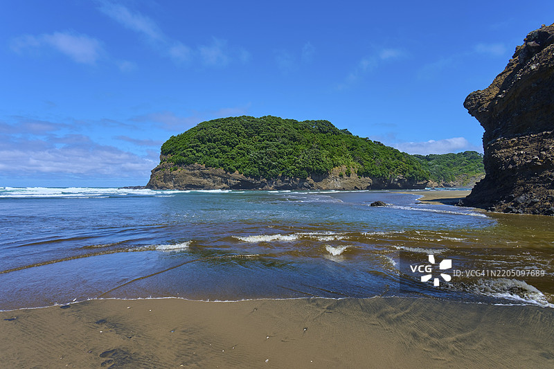 宁静的海滩，绿丘和温柔的波浪在蓝天之下，贝塞尔斯海滩，特亨加，奥克兰，新西兰，南太平洋图片素材