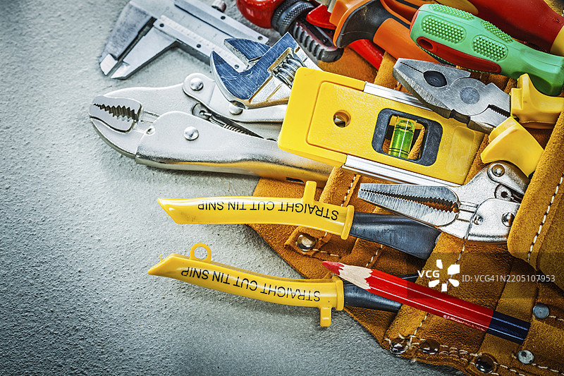 混凝土背景上的工具带中的一套建筑工具图片素材