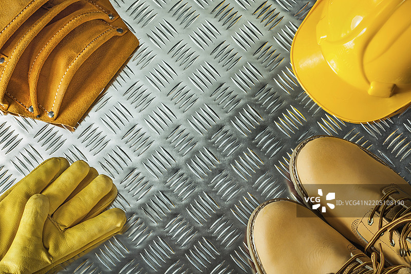 安全手套、靴子、建筑头盔和工具带在波纹金属纹理上图片素材