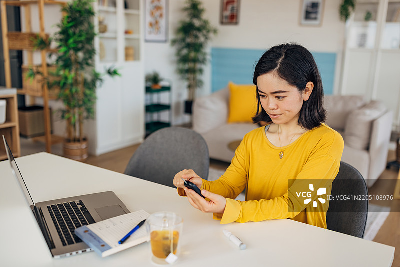日本女性在家中测量血糖以便早期发现和预防健康并发症图片素材
