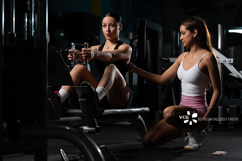 私人教练在健身房指导客户使用划船机锻炼图片素材