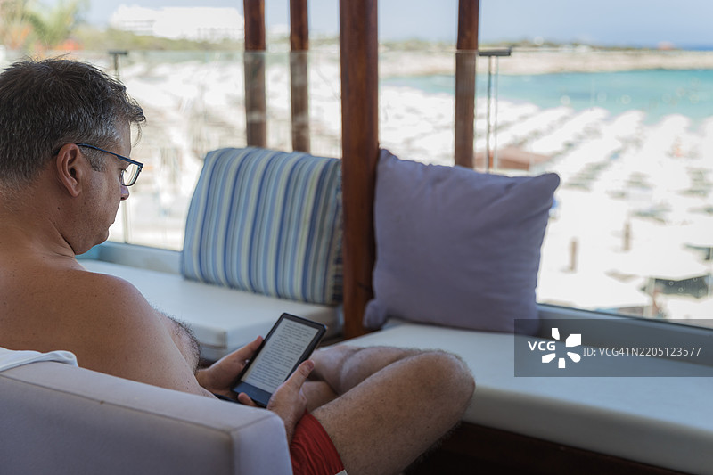 男人在海滩上使用电子书阅读器图片素材