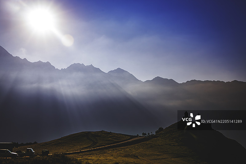 戏剧性的高加索山脉风景，著名的格尔盖提三位一体教堂轮廓矗立在山丘上图片素材