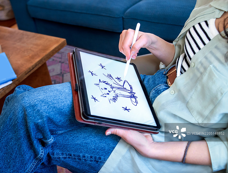 在家工作的平面艺术家。女人在客厅里创作一幅猫与星星的素描。图片素材