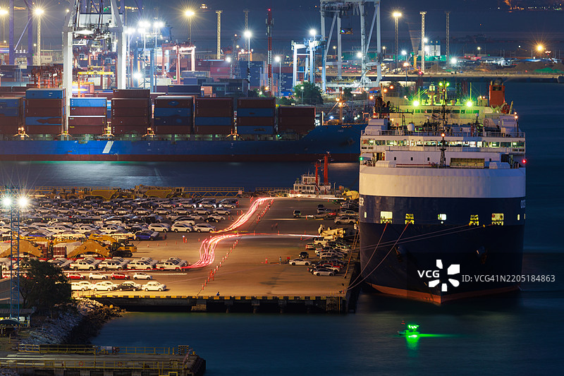 工业货运港口，门式起重机正在装载集装箱船，展示了海洋运输行业和全球贸易运作，夜间的主要航运中心。图片素材