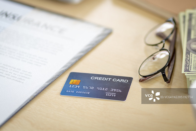 商务人士的桌子上有信用卡、美元、眼镜和一杯咖啡。图片素材