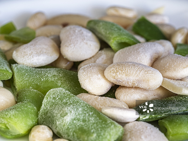 厨房里盘子上的冷冻蔬菜（青豆和红腰豆）正在解冻。图片素材
