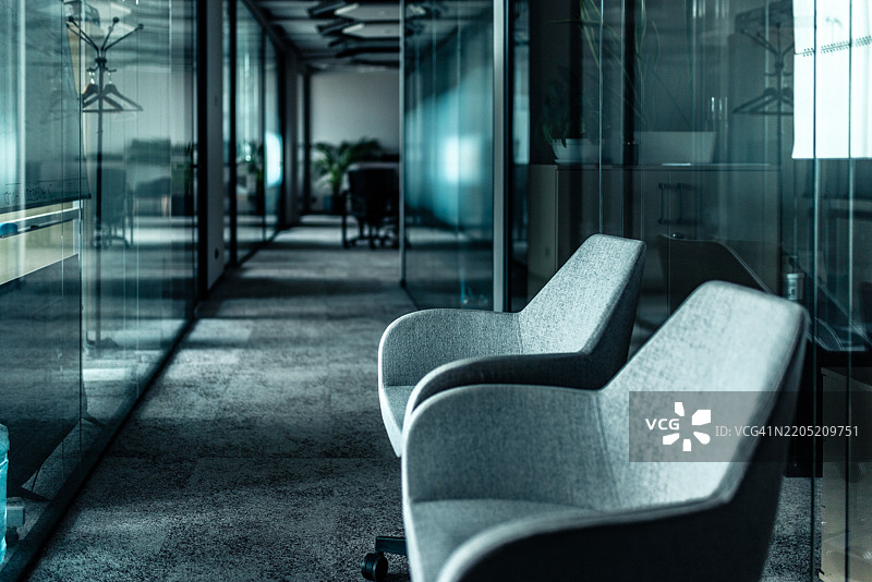 现代办公室走廊，配有扶手椅和明亮灯光下的玻璃墙图片素材