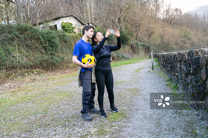 年轻情侣在山中踢完足球后自拍图片素材