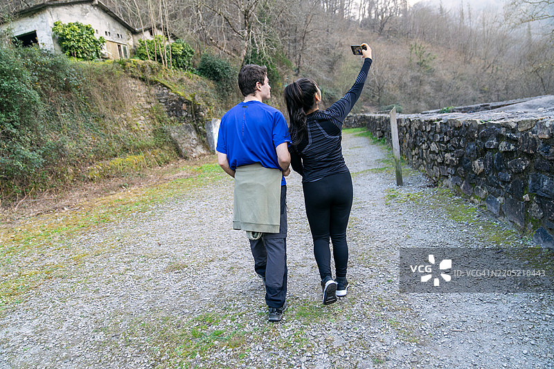 徒步旅行者在古老石墙旁边走路时自拍图片素材