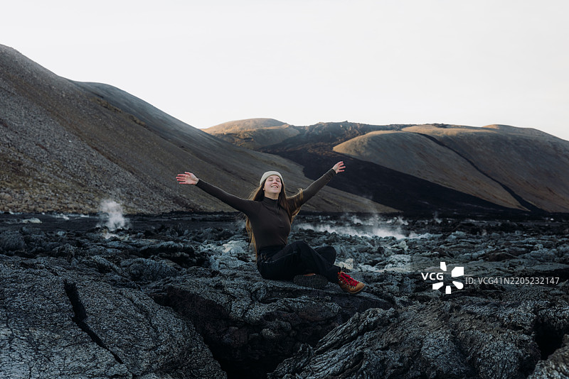 愉快的女性欣赏冰岛法格拉达尔火山喷发时的新鲜熔岩黑色火山景观图片素材