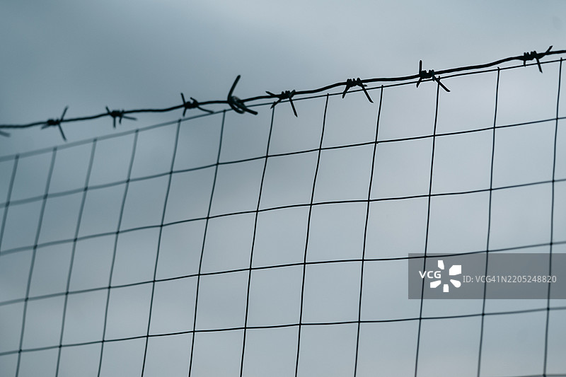 铁丝网在阴云密布的天空下形成边界图片素材