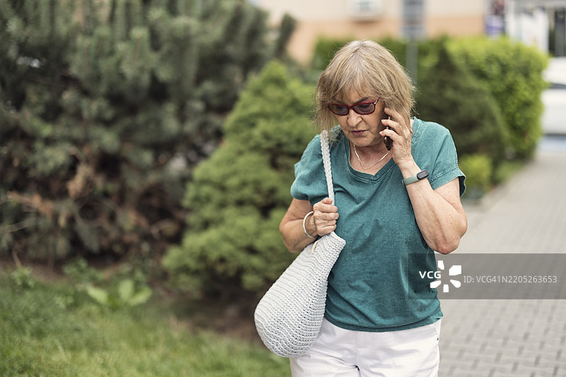 一位老年女性一边走路一边打电话图片素材