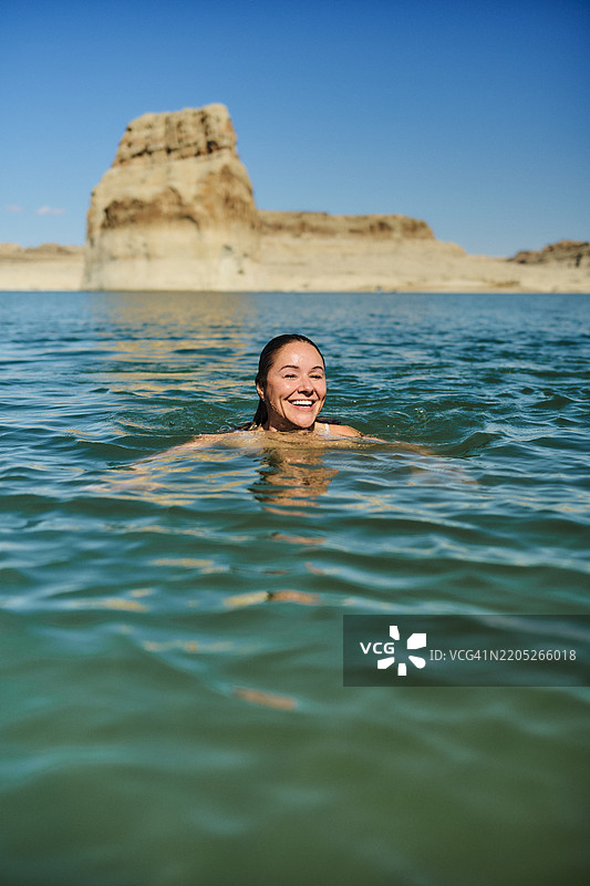 女人在峡谷下的湖中游泳图片素材