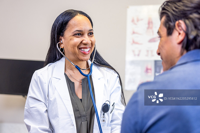 西班牙裔男性在医生预约中，黑人女性医生正在测量血压图片素材