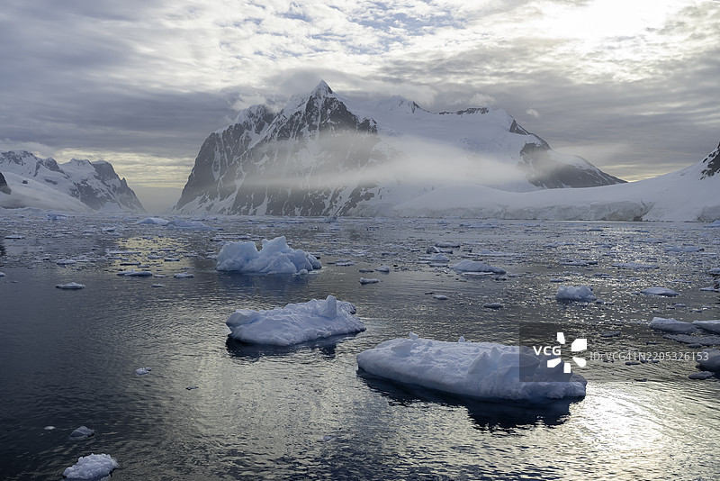 日落时分，南极拉梅尔海峡的冰山和山脉的鸟瞰图。图片素材