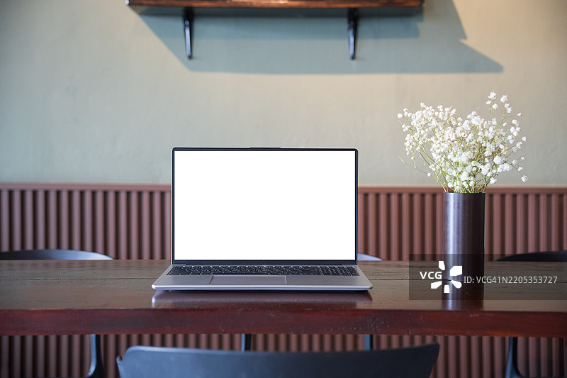 咖啡馆背景下桌子上的笔记本电脑空白屏幕。咖啡店桌子上的笔记本电脑空白屏幕，背景模糊。图片素材