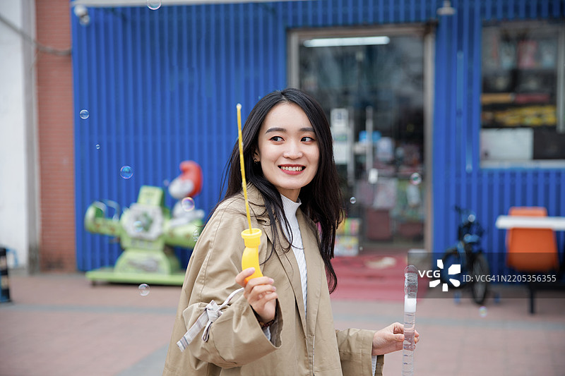 一位美丽的女性在城市中玩水泡和肥皂泡泡图片素材