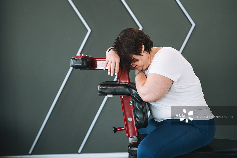 疲惫的中年丰满女性在健身房的有氧运动器械上锻炼图片素材