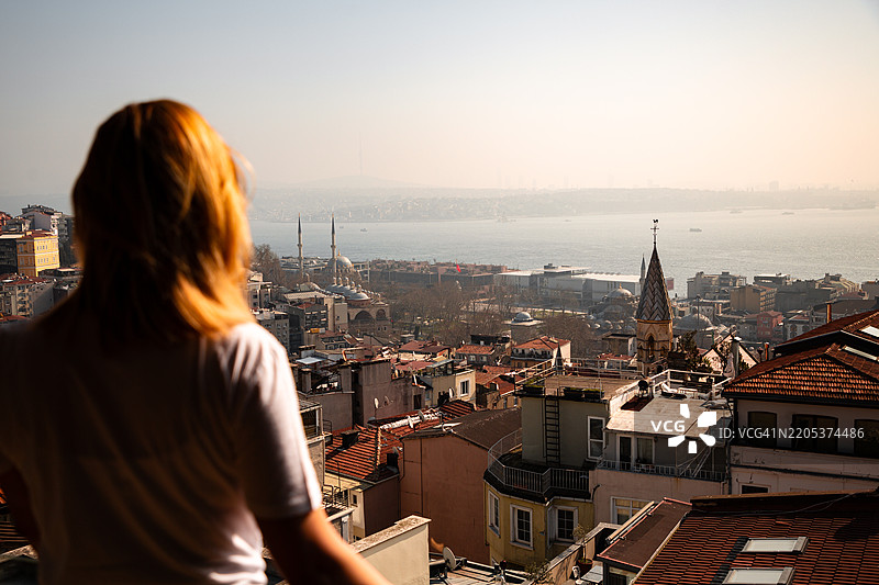 年轻女性在阳台上欣赏伊斯坦布尔的晨景图片素材