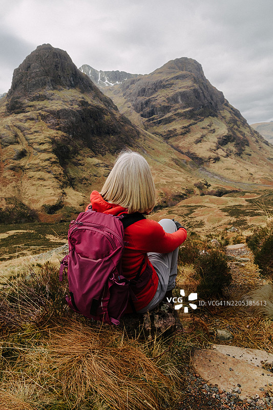 一位女性在苏格兰格伦科的三姐妹山前休息。图片素材