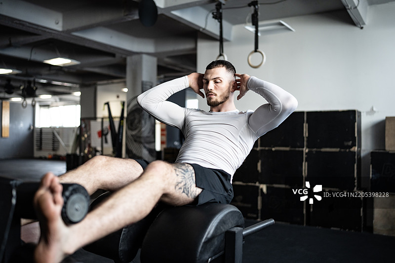 男子在健身器械上进行腹部锻炼图片素材