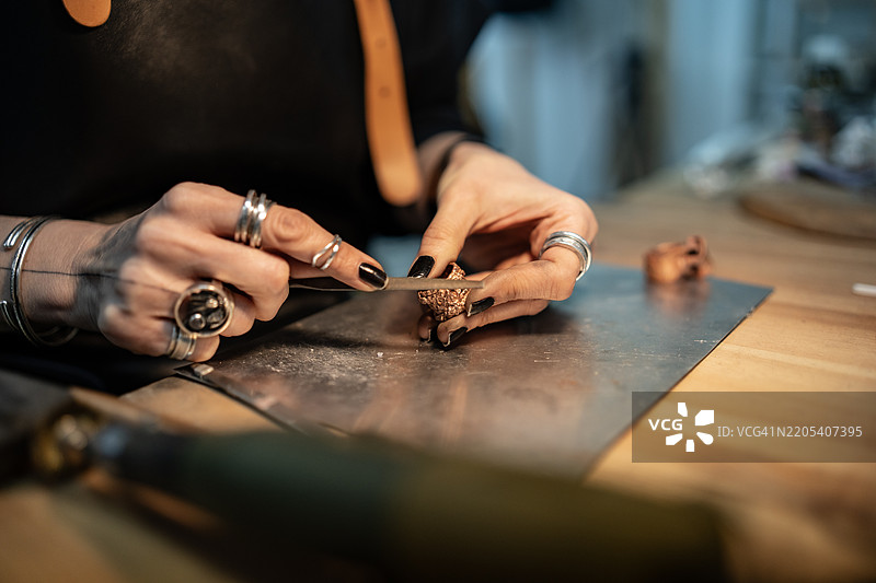 在工作台上用金属工具精确制作珠宝的双手图片素材