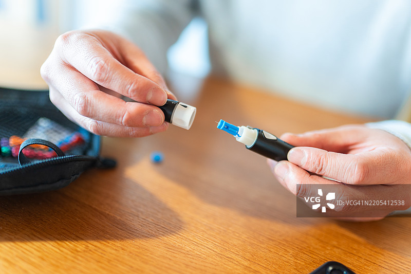 中年亚洲男性在家中使用血糖监测仪检查血糖水平图片素材