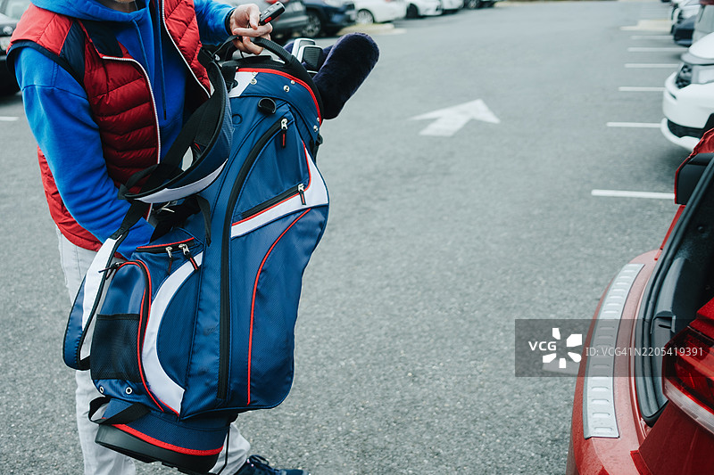 男子从汽车后备厢中取出高尔夫球杆图片素材