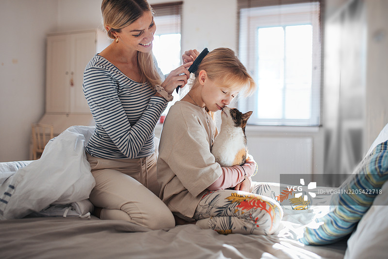 母亲在床上为女儿梳头。图片素材