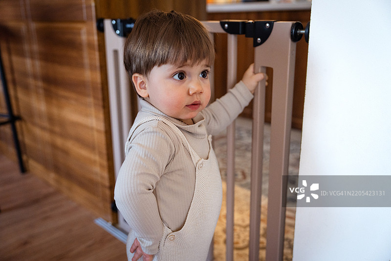 幼儿男孩站在婴儿门前图片素材