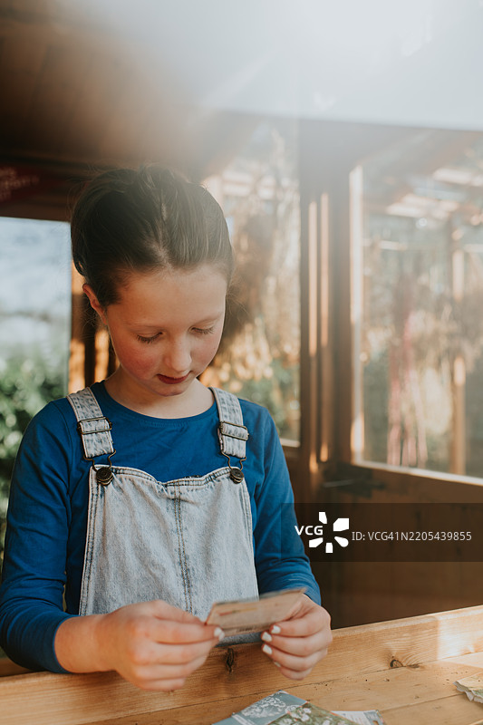 一个快乐的小女孩在种植棚里查看种子包装上的说明。图片素材