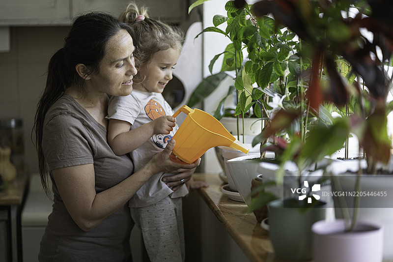 生态意识。Z世代女孩帮助妈妈浇水。图片素材