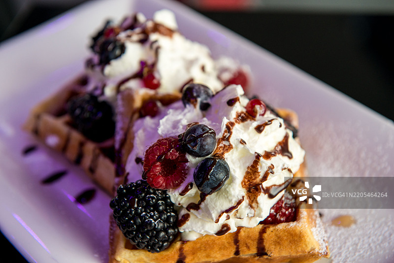 盘子上的华夫饼配浆果、奶油和巧克力糖浆图片素材
