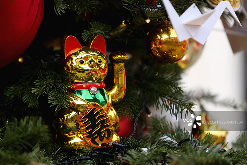 户外的中国新年。金色招财猫与纸鹤和节日装饰的圣诞树。图片素材
