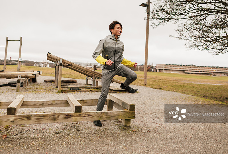 一名男子在户外健身房锻炼腿部。图片素材