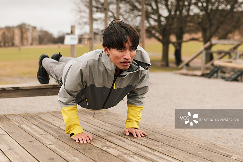一名男子在户外健身房做俯卧撑。图片素材
