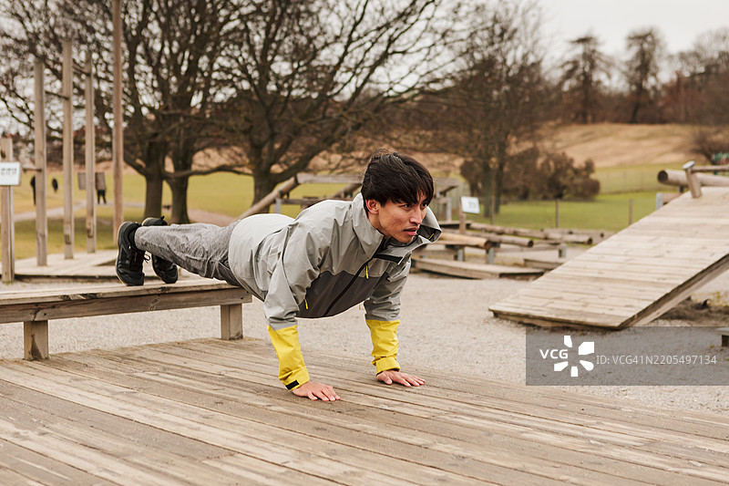 一名男子在户外健身房做俯卧撑。图片素材