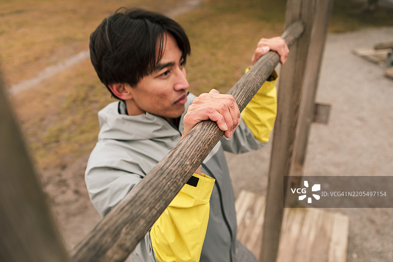 一名男子在户外健身房做引体向上。图片素材