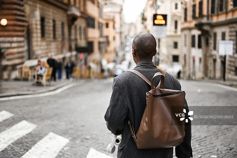 年轻男子在罗马走路，戴着耳机，背着背包图片素材