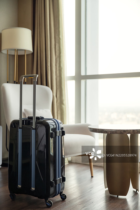 酒店明亮的客厅里放着一个行李箱。图片素材