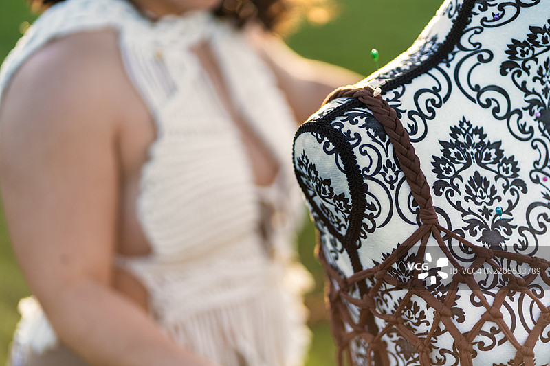 在花园里，裁缝正在为模特制作一件挂毯上衣。图片素材