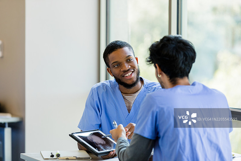 两名医疗专业人员在平板电脑上讨论患者的医疗记录图片素材