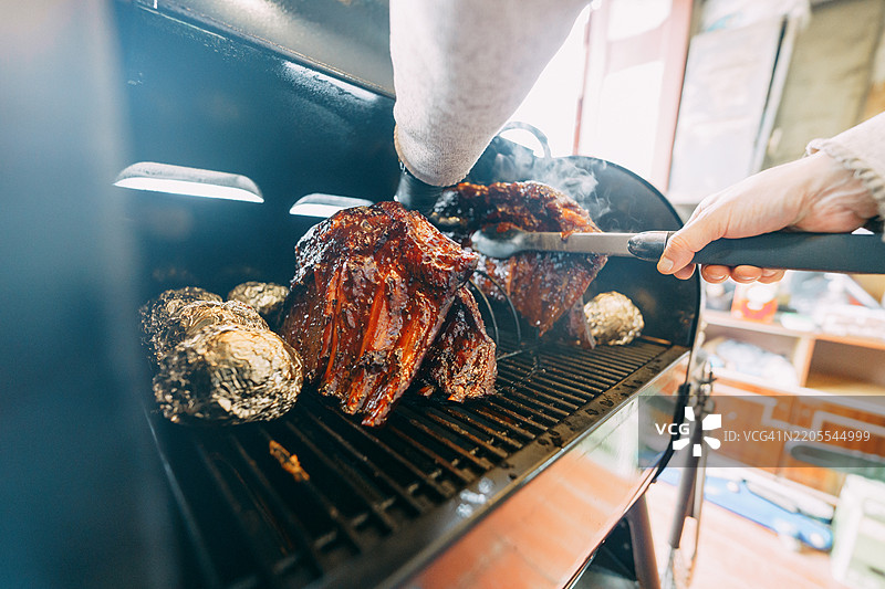 厨师在烟熏炉中烤制美味的烧烤肋排和土豆图片素材