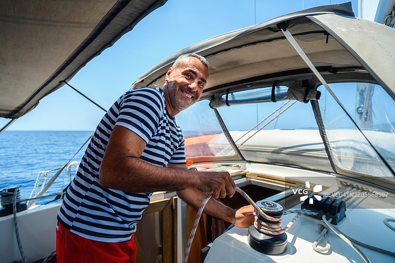 在帆船上使用绞盘的男子图片素材