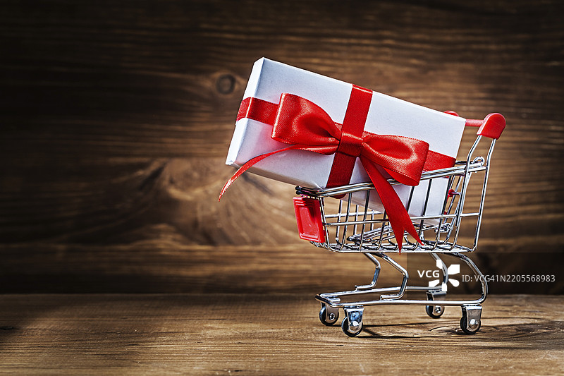 复古木材上的购物车里的白色礼品盒图片素材