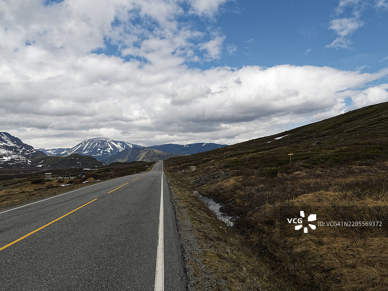 通往被雪覆盖的山脉的空旷道路图片素材
