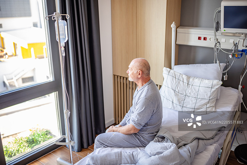 一位老年人在医院病房中接受护理，静静地回忆着他的康复之旅。图片素材